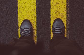 Person in Gray Sneakers Standing on Pedestrian Lane