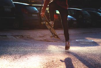 Person in Red Long Sleeved Shirt and Black Skinny Pants Riding a Skateboard