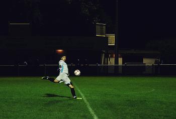 Person Kicks Soccer Ball in Field
