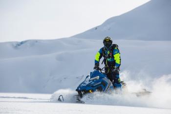 Person Rides on Blue Snowmobile at Daytime