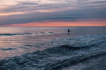 Person Standing in the Sea during Sunset
