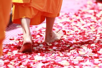 Person Wearing Orange Dress Walking on Petals during Daytime