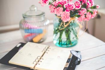 Personal organizer and pink flowers on desk