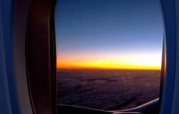 Photo of Airplane Window With View of Clouds and Golden Hour