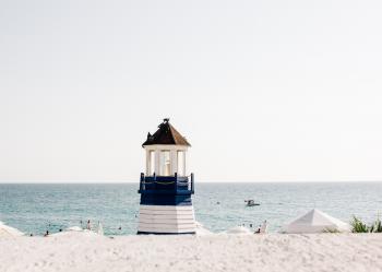 Photo of Blue and White Painted Lighthouse Near the Beach