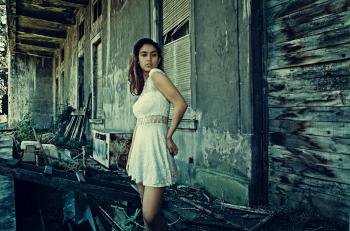 Photo of Woman Wearing White Dress Standing Near Abandoned Building