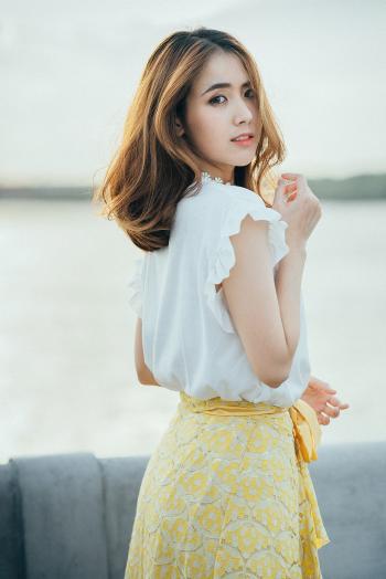 Photo of Woman Wearing White Sleeveless Shirt and Yellow Floral Skirt Near Body of Water