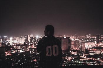 Photography of a Person Watching over City Lights during Night Time