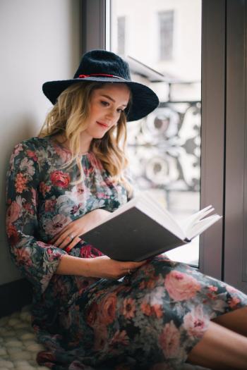 Pregnant Woman Wearing Green, Red, and White Floral Dress Reading a Book Near Window