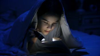 4k video of girl with flashlight reading scary story under blanket ...