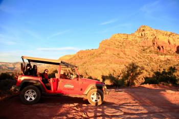 Red All-terrain Vehicle on Brown Rock Field during Sunset