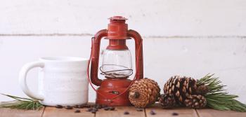Red Kerosene Lantern Beside White Ceramic Mug on Brown Wooden Table