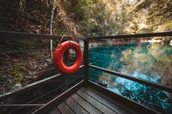Red Life Buoy Hanging on Brown Wooden Balcony