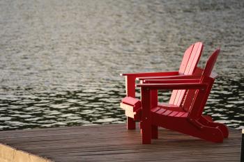 Red Wooden Lounge Chair on Brown Boardwalk Near Body of Water during Daytime