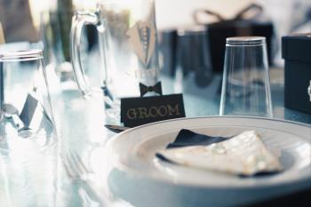Round White Ceramic Plate Near Glass Cups and Groom Sign