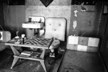 Scary old prison cell with a toilet and a chessboard