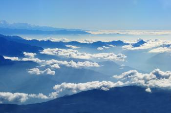 Scenic View of Clouds over Mountains Against Blue Sky