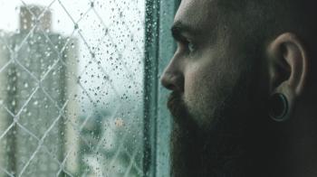 Selective Focus Photography of Man Staring on Glass Window Filled With Droplets