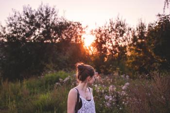 Selective Focus Photography of Woman Standing in the Middle of Grasses and Flowers during Golden Hour