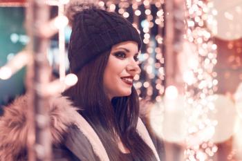 Selective Focus Photography of Woman Wearing Black Cap and Gray Parka Jacket Surrounded by Lights