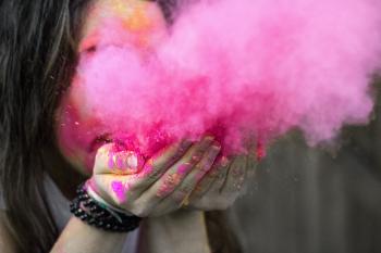 Shallow Focus Photograph of Woman Blowing Pink Powder