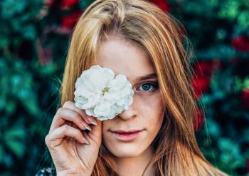 Shallow Focus Photography of Woman Holding White Flower
