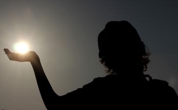 Silhouette of a child holding the sun