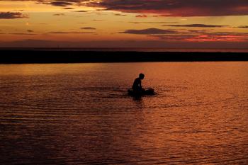 Silhouette of Person on Body of Water during Sunset