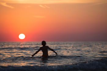 Silhouette Photo of Child on Body of Water during Golden Hour