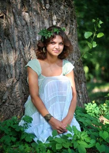 Smiling Woman Wearing Green Leaf Crown With Green and White Sleeveless Dress Sitting in Green Leaf during Day Time