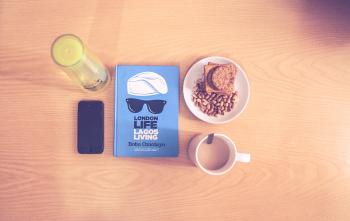Space Gray Iphone Beside Blue Labeled Book Near White Ceramic Cup With Liquid Content