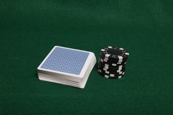 Stack of black poker chips next to cards