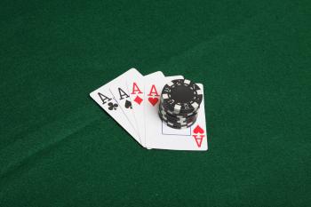 Stack of black poker chips on four aces.