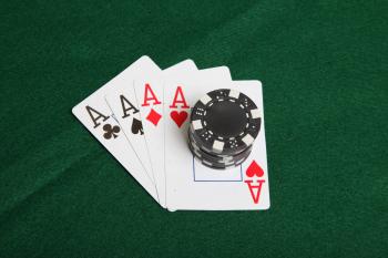 Stack of black poker chips on four aces.