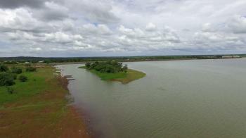 The drone flies over the shore of a lake. An island is near. The ...