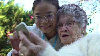 4K Smiling asian granddaughter showing and teaching mobile phone to ...
