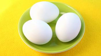three raw eggs on green rotating plate on yellow table Stock Video ...
