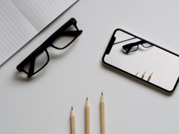 Three Pencils, Eyeglasses, and Smartphone on White Table