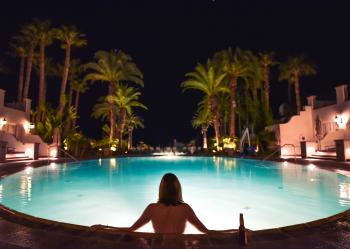 Topless Woman in Pool Facing Trees during Night Time