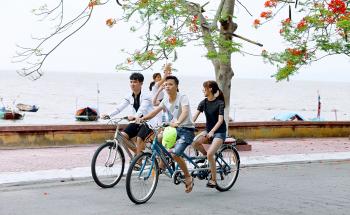 Two Boys and One Girl Riding Bicycles on Road Beside Body of Water