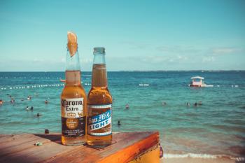 Two Corona Extra and San Mig Light Beers on Top of Brown Wooden Plank Near Beach