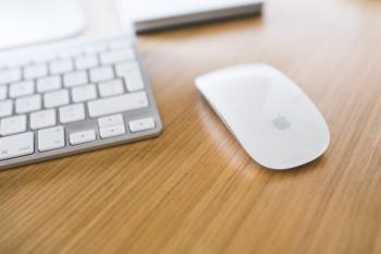 White Apple mouse and keyboard on a wooden desk