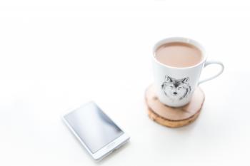 White desk with a cup of coffee and mobile phone