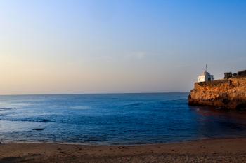 White Lighthouse Near Sea Under Blue Sky