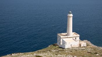 White Lighthouse on Cliff Near Body of Water