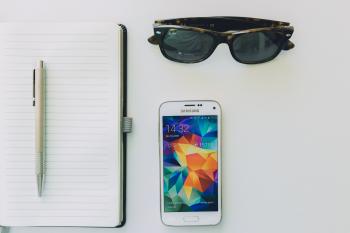 White Samsung Smartphone Beside Sunglasses,pen and White Notebook