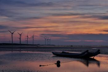 Windmills Behind Canoe Boat during Sunset