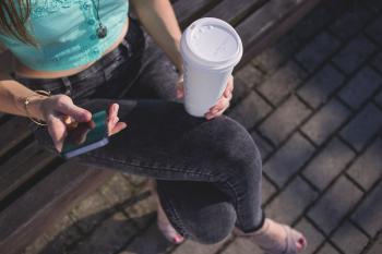 Woman Holding White Disposable Cup and Smartphone