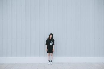 Woman in Black Elbow Sleeve Shirt and Black Shorts Standing Behind White Wall