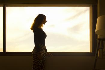 Woman in Black Long Sleeve Shirt and Tribal Leggings Standing by the Window during Daytime